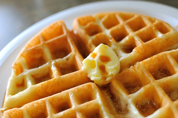 Waffles in syrup on a white plate