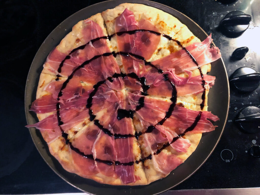 Top-down view of the final prepared pizza, featuring a balsamic glaze swirl